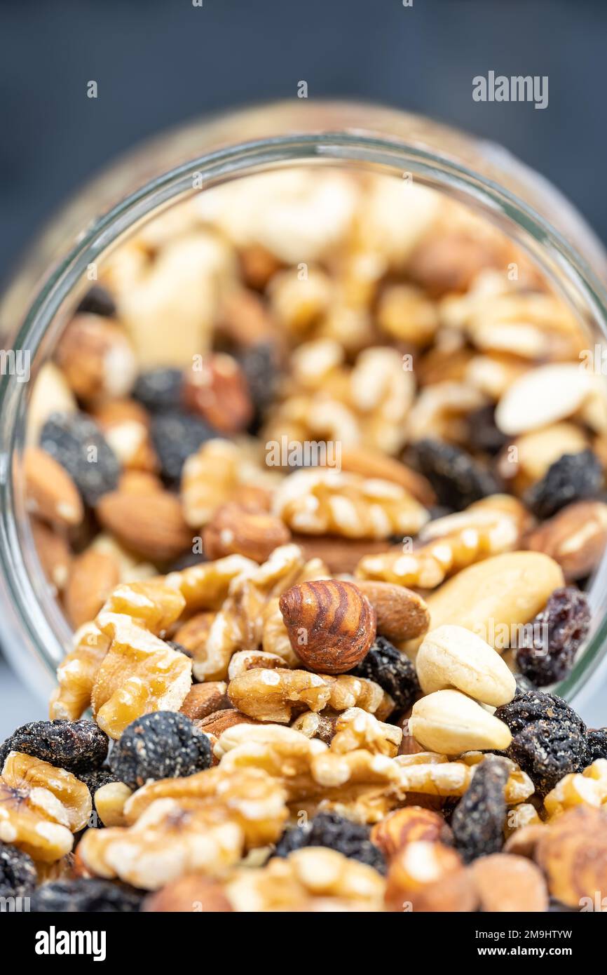 Glasbehälter mit verschiedenen Nüssen mit Mandeln, Haselnüssen, Cashews und Rosinen in einem Makrofoto. Stockfoto
