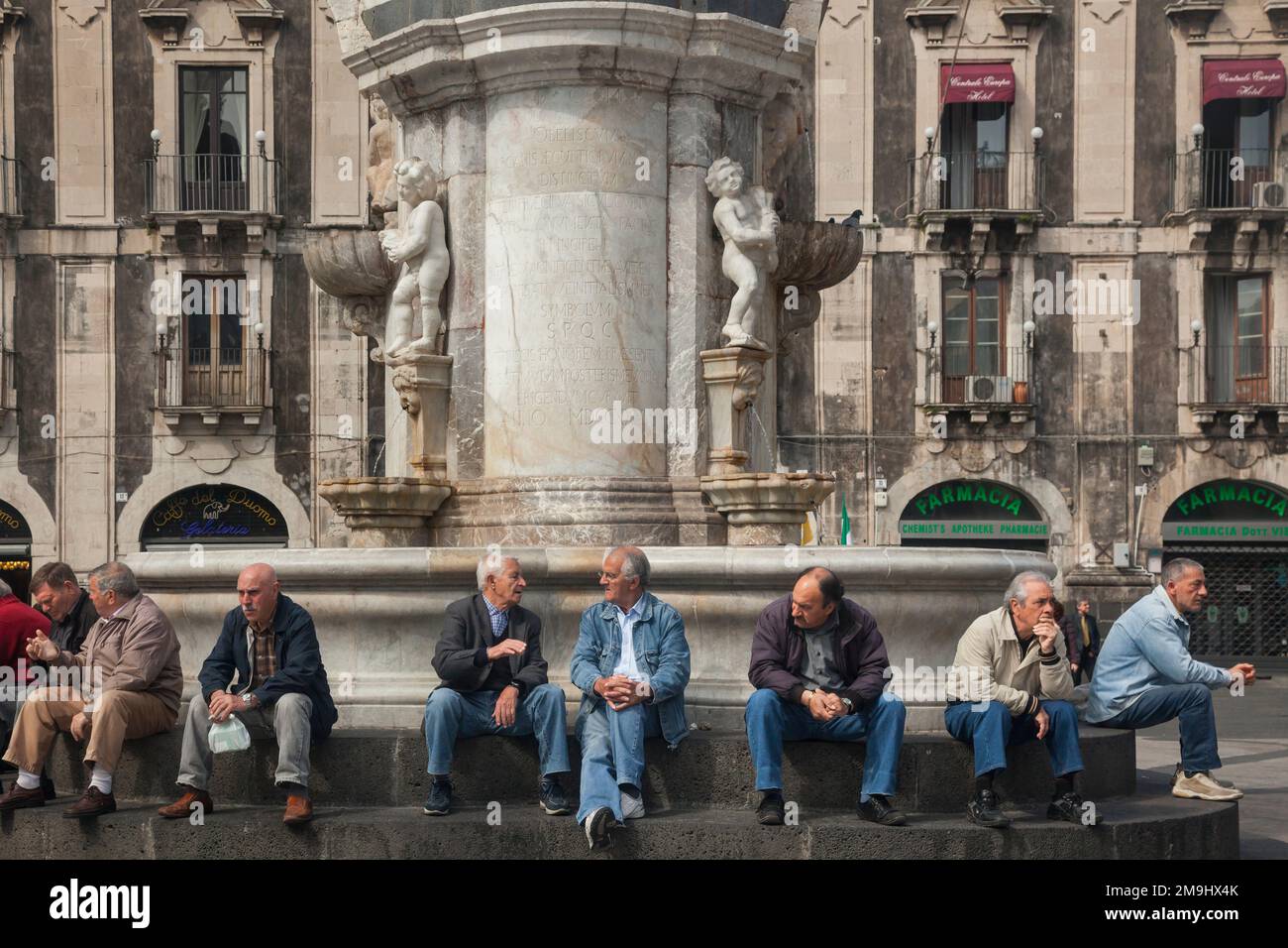 Geselliges Treffen alter Männer in der Fontana dell' Elefante auf der Piazza Duomo, Catania, Sizilien Stockfoto