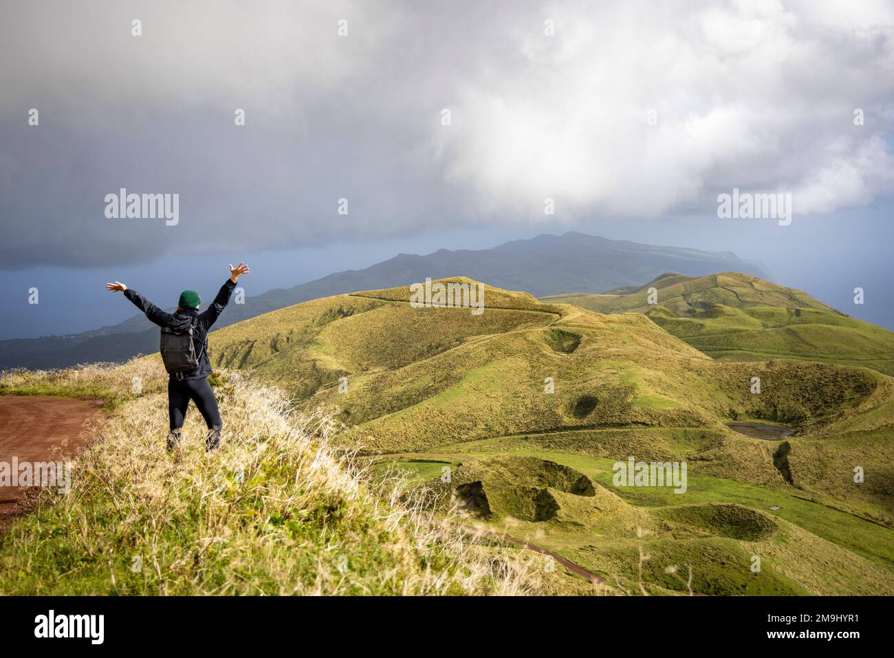 Glückliche Frau mit erhobenen Armen, die den Blick auf das zentrale Hochland auf der Insel São Jorge auf den Azoren genießt Stockfoto