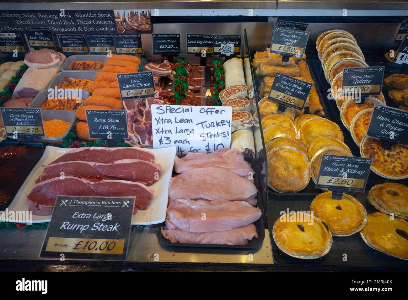 J Thompson's Butchers Schaufenster in Northallerton North Yorkshire England UK mit einer großen Auswahl an zubereitetem Fleisch zu Preisen von 2023 Stockfoto
