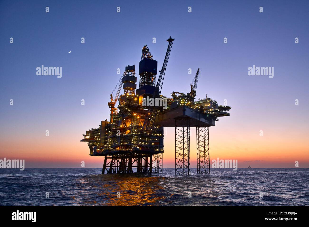 Offshore-Erdöl- und -Erdgasplattform im Meer bei Sonnenuntergang. Bocken Sie die Rohölförderung im Ozean auf. Stockfoto