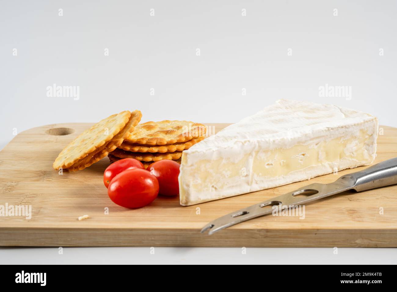 French Brie Weichkäse serviert Pflaumentomaten und dünne Cracker Stockfoto