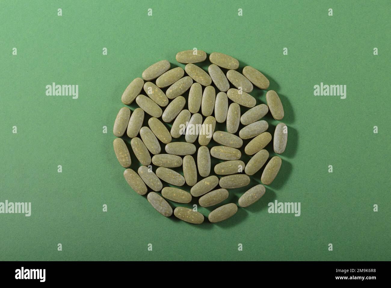 Kräuter- und Vitamin-Grüne-Pillen auf grünem Hintergrund Stockfoto