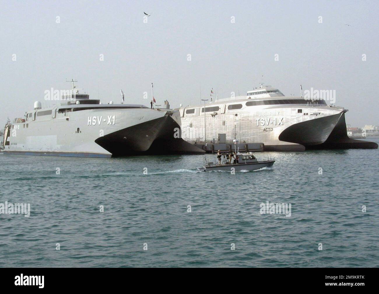 030225-N-1050K-001. [Complete] Scene Caption: Sealift-Fahrzeuge der US Navy (USN) und der US Army (USA) sitzen zusammen auf der Pier-Seite unter den wachsamen Augen der US-amerikanischen und kuwaitischen Hafenpatrouille. Die Navy Joint Venture (HSV-X1) (links) und die Army's Spearhead (TSV-1x) sind Hochgeschwindigkeitskatamarane, die von WERFTEN VON INCAT Australia entworfen und gebaut wurden. Der Entwurf des gemeinsam genutzten Schiffs wurde vom Navys Warfare Development Command in enger Partnerschaft mit Elementen der USA, der USN, des US Marine Corps (USMC) und der US Coast Guard (USCG) koordiniert. Die Schiffe sind beeindruckend schnell und können Truppen bewegen und ausrüsten Stockfoto