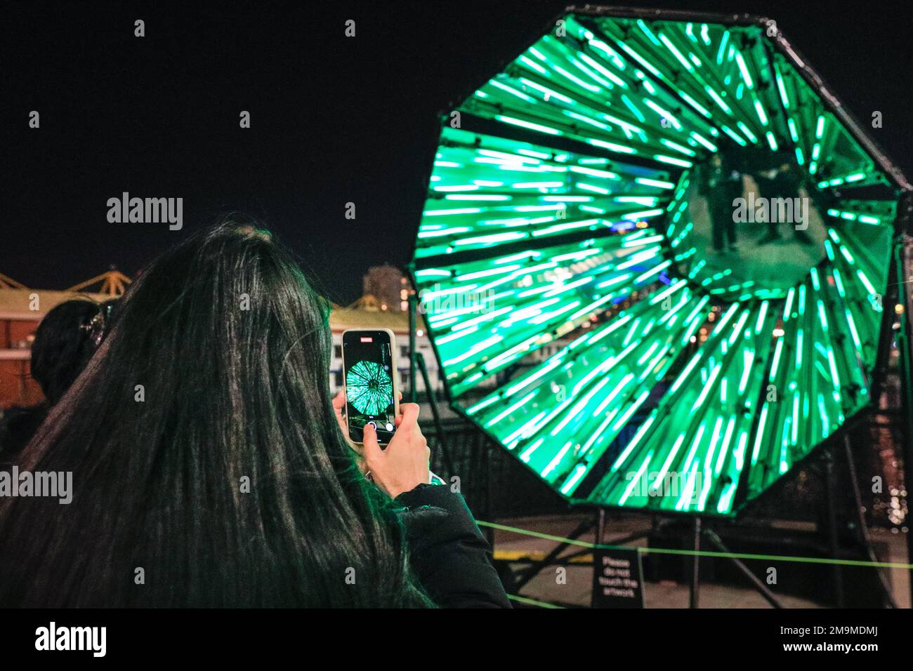 London, Großbritannien. 18. Januar 2023. Die Menschen sehen und fotografieren Out of the Dark von Tom Lambert, direkt vor dem Crossrail Place, einer audiovisuellen Lichtanlage, die Raum für Selbstreflexion und positive Einstellung bietet. Das jährliche Winter Lights Festival startet heute mit 22 Lichtinstallationen und beeindruckenden Kunstausstellungen rund um Canary Wharf in London. Das öffentliche Festival läuft bis zum 28. Januar und kann kostenlos besucht werden. Kredit: Imageplotter/Alamy Live News Stockfoto