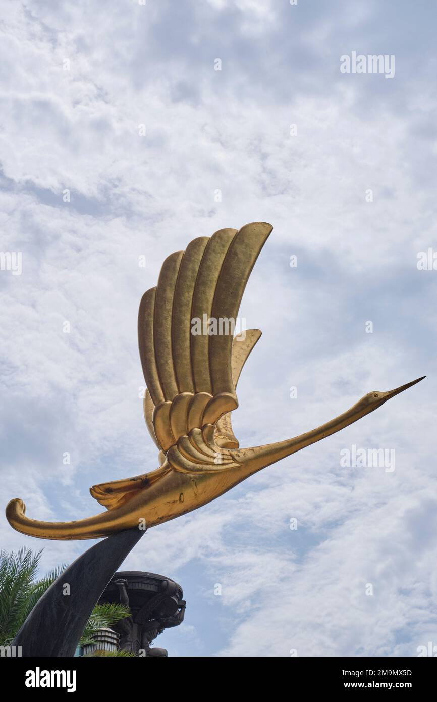 Ein vertikales Bild einer goldenen Kranskulptur auf dem Hof des Bürogebäudes Parkview Square in der North Bridge Road, Singapur Stockfoto