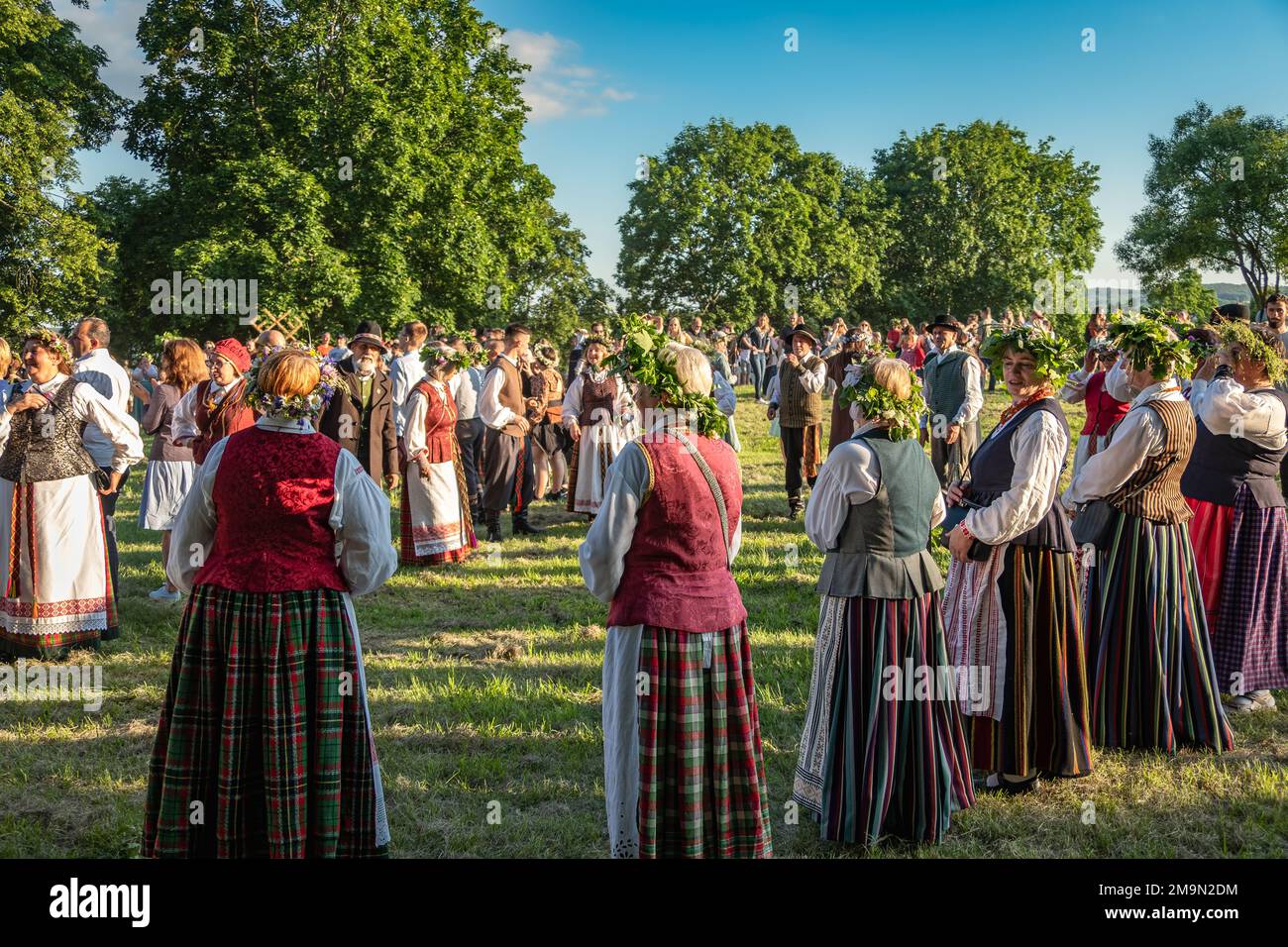 Menschen in Volkskleidung und Kräuterkränzen feiern den Mittsommer in Litauen Stockfoto