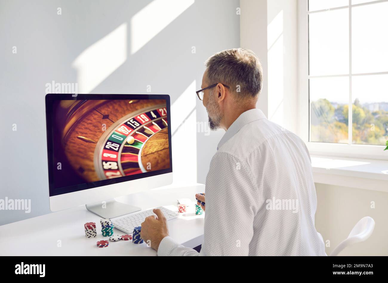 Ein Mann, der Online-Casino-Glücksspiel am Computer spielt Stockfoto
