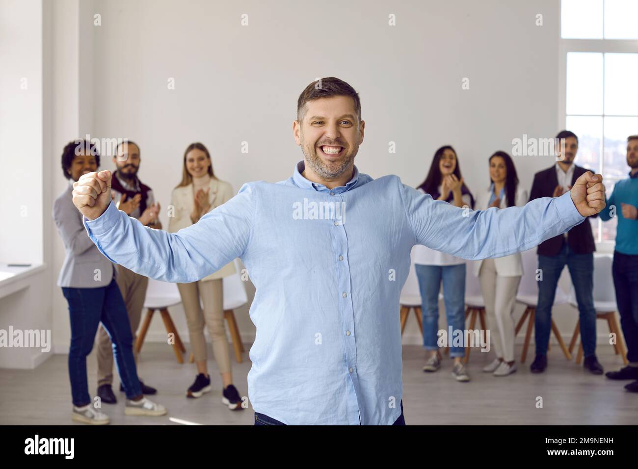 Glücklicher, lustiger, selbstbewusster Geschäftsmann, der seinen Erfolg mit einem Mitarbeiterteam feiert Stockfoto