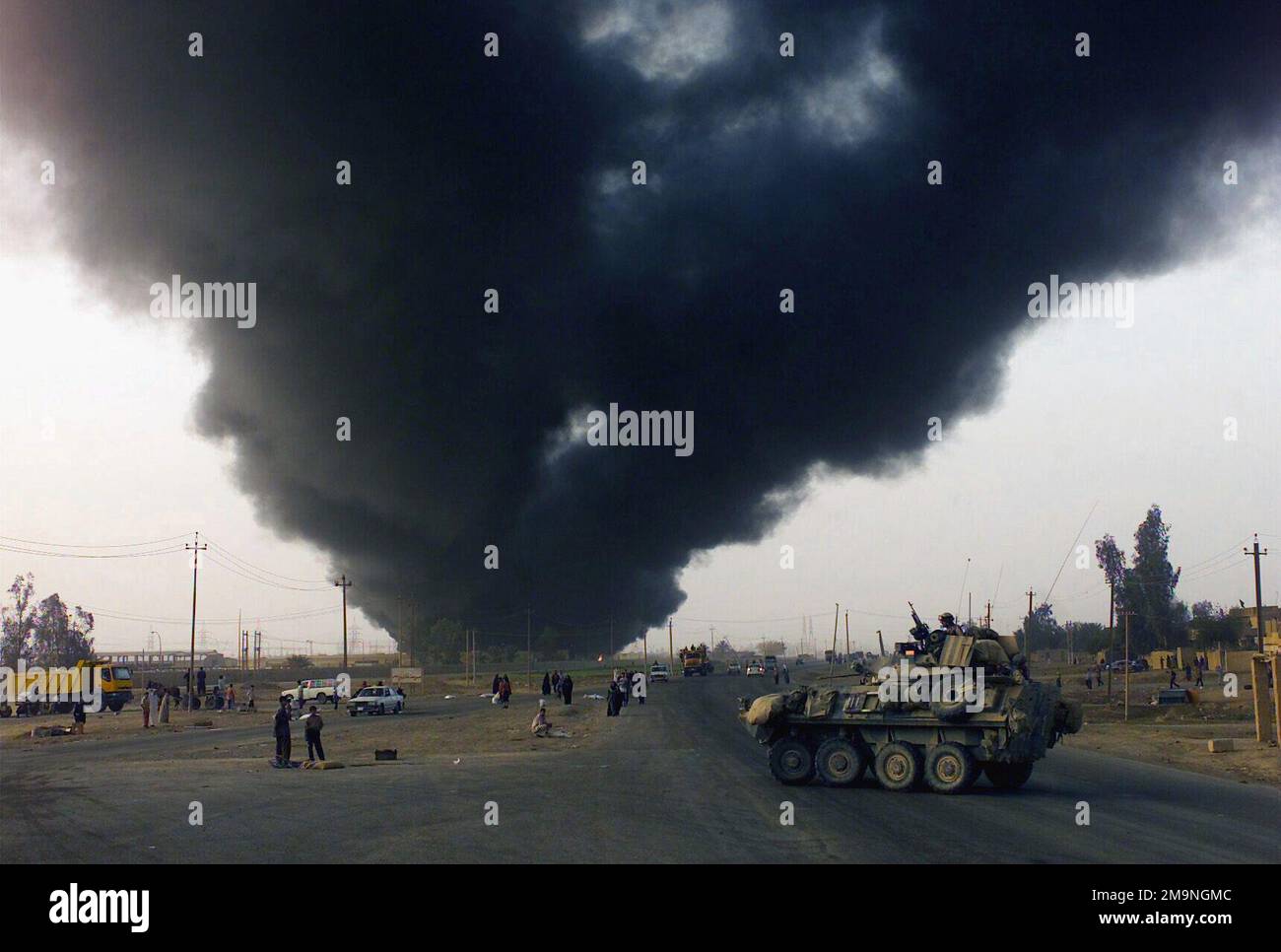 Rauch aus einem brennenden Ölfeld steigt in die Luft, während die Marines des US Marine Corps (USMC), die der D/ Company, 1. Aufklärungsbataillon der leichten Rüstung, 1. Marine Division, ihr leichtes gepanzertes Fahrzeug (LAV-25) während der Operation IRAQI FREEDOM nach Bagdad, Irak, fuhren. Operation/Serie: IRAKISCHE FREIHEITSBASIS: Bagdad Land: Irak (IRQ) Stockfoto