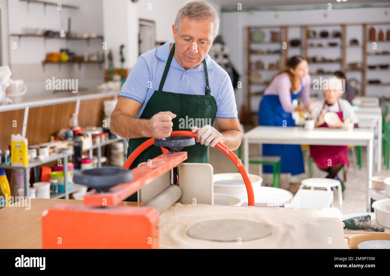 Männlicher Töpfer arbeitet mit der maschinellen Tonpresswalze Stockfoto