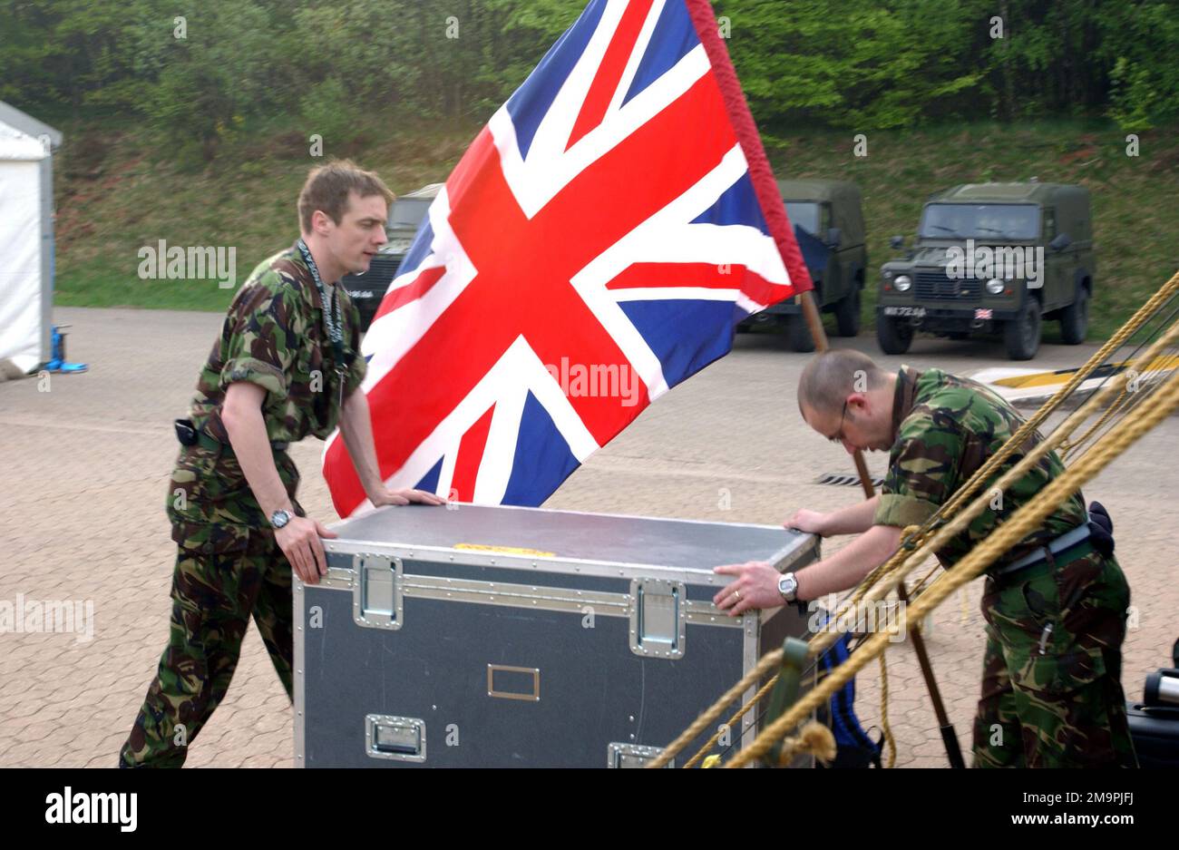 Die Soldaten der Royal Army (Britische Armee) schieben die Ausrüstung an der National FÄHNRICH vorbei, während sie Operationen in Lager Aulenbach, Deutschland, während des von der US European Command (USEUCOM) gesponserten gemeinsamen VORHABENS einleiten. Bei dieser Übung handelt es sich um eine Partnerschaft für den Frieden (Partnership for Peace, PfP), die von Deutschland veranstaltet wird und die weltweit größte Übung im Bereich Informations- und Kommunikationssysteme ist, die sich hauptsächlich auf Interoperabilitätstests und -Dokumentation in den Bereichen Kommando, Steuerung, Kommunikation und Computer (C4) konzentriert. Betreff Operation/Serie: KOMBINIERTE ENDEAVOR-Basis: Lager Aulenbach Bundesland Rheinland-Pfalz Land: Deutschland / Ge Stockfoto
