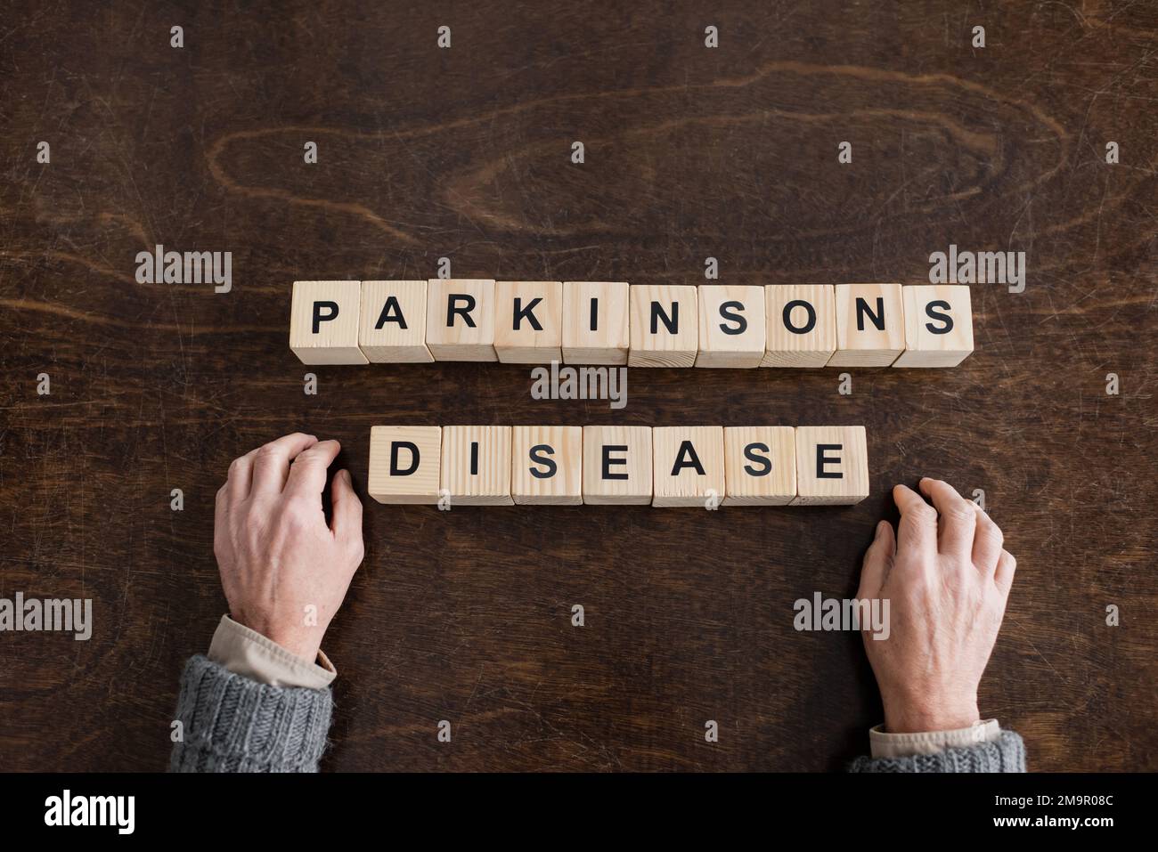 Draufsicht des gekürzten Seniorenmannes in der Nähe von Würfeln mit inschrift der parkinsons-Krankheit auf einem Holztisch, Stockbild Stockfoto