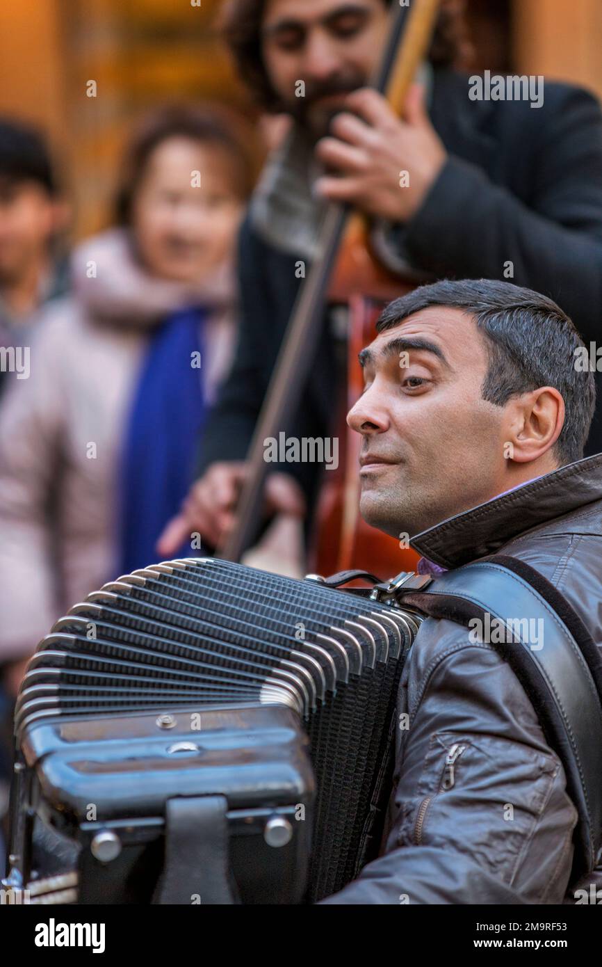 Ein Straßenmusiker tritt mit seinem Akkordeon in einer Fußgängerzone in Venedig auf. Stockfoto