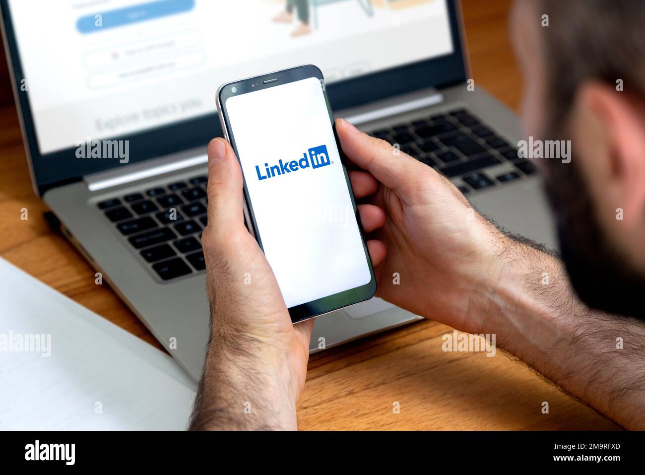 LinkedIn-App auf dem Smartphone-Bildschirm. Mann mit einem Telefon mit einer professionellen und geschäftsorientierten Social-Network-Service-Anwendung. Stockfoto