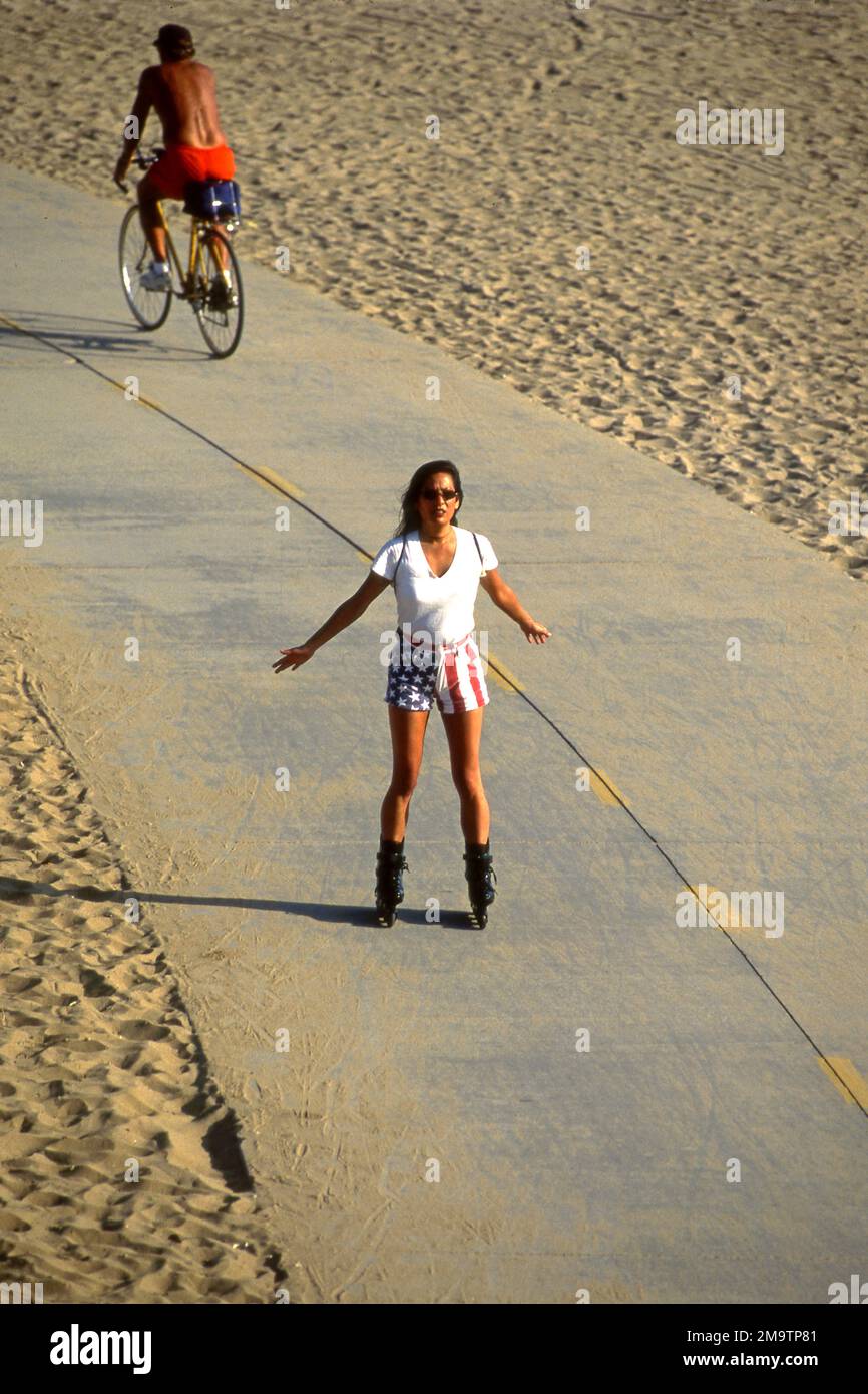 Eine Frau mit Shorts mit US-Flagge auf dem Radweg zwischen Venice und Santa Monica Beach in Los Angeles, Kalifornien Stockfoto