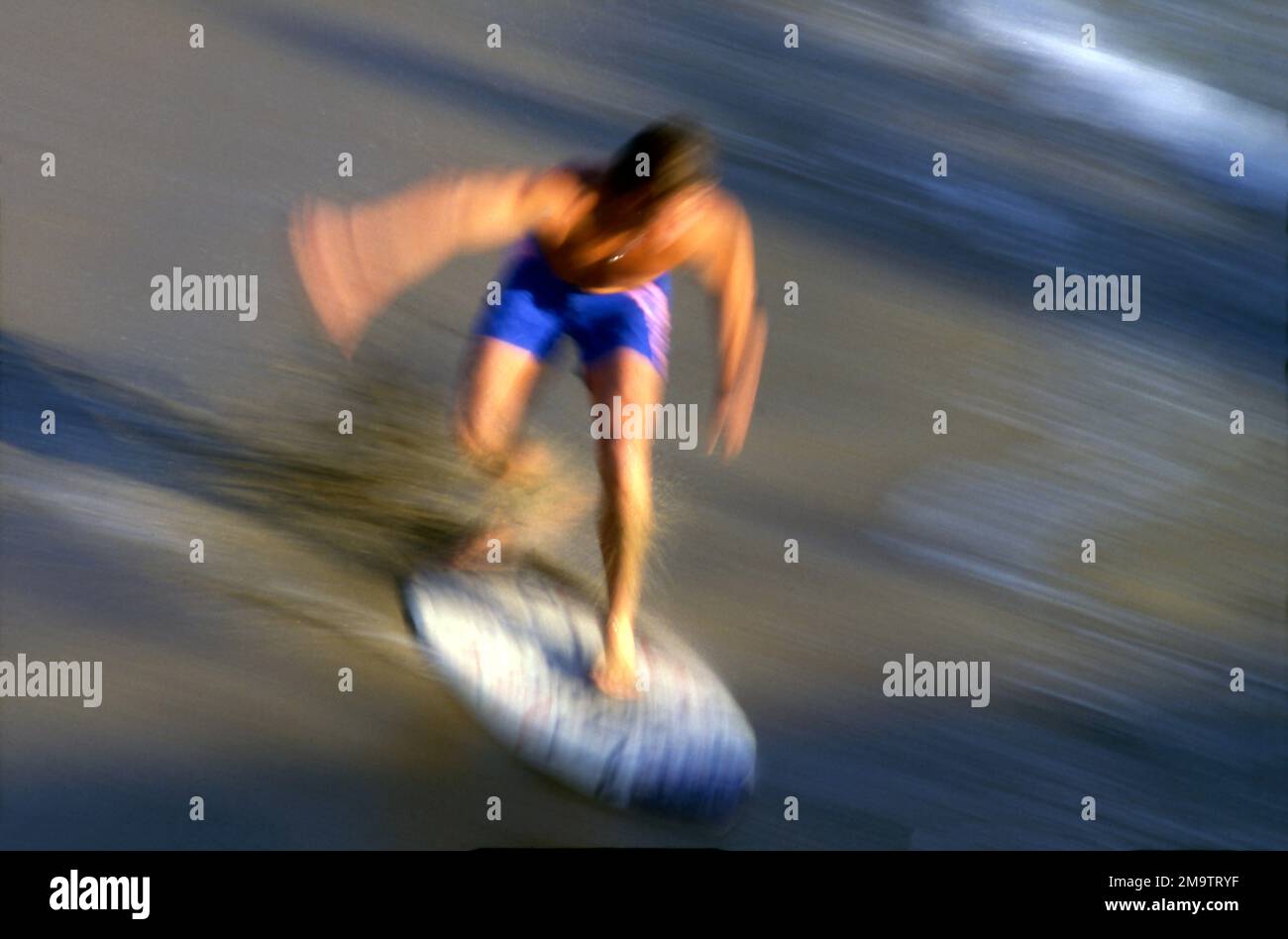 Verschwommenes Schwenken eines Skim Boarders am Strand in Südkalifornien Stockfoto
