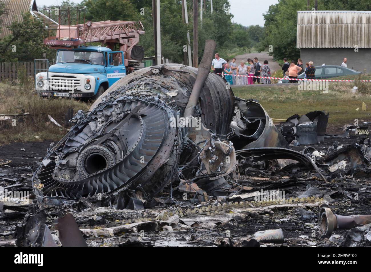 FILE - Local citizens, background, look at the site of a crashed Malaysia Airlines passenger plane near the village of Rozsypne, Ukraine, eastern Ukraine on July 18, 2014. A Dutch court on Thursday is set to deliver verdicts in the long-running trial of three Russians and a Ukrainian rebel for their alleged roles in the shooting down of Malaysia Airlines flight MH17 over conflict-torn eastern Ukraine. (AP Photo/Dmitry Lovetsky, File) Stockfoto