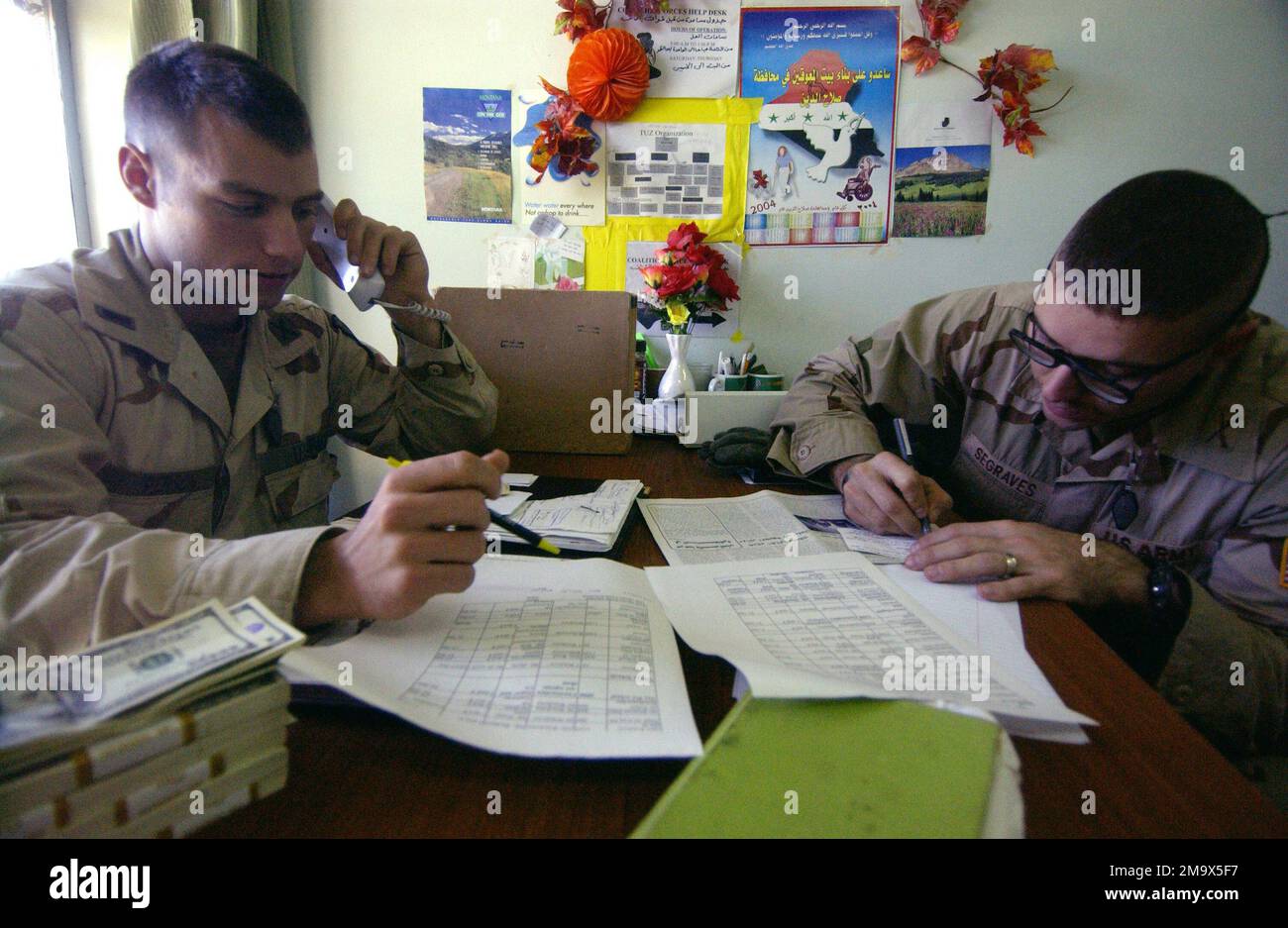 Kapitän der US-Armee (USA) (CAPT) Segraves und Leutnant (LT), Offiziere der zivilen Militäroperation (CMO) mit dem 1. Bataillon, 508. Infanterie, treffen sich in ihrem Büro im Regierungsgebäude in der Innenstadt von Tuz, Irak (IRQ), um die Zuweisung von Mitteln für verschiedene Bürgerprojekte in der Gegend um Tuz zu erörtern; Während der Operation IST die IRAKISCHE FREIHEIT. Operation/Serie: IRAKISCHE FREIHEITSBASIS: Kirkuk Land: Irak (IRQ) Stockfoto