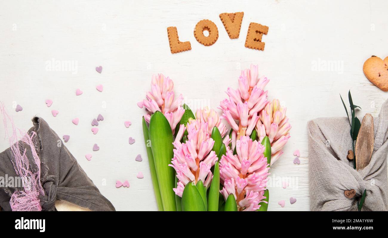 Konzept zum Valentinstag ohne Verschwendung. Umweltfreundliches Geschenktuch in Furoshiki-Stil, hausgemachte Süßigkeiten und Kekse als Geschenkideen, Frühlingsblumen. Bis Stockfoto