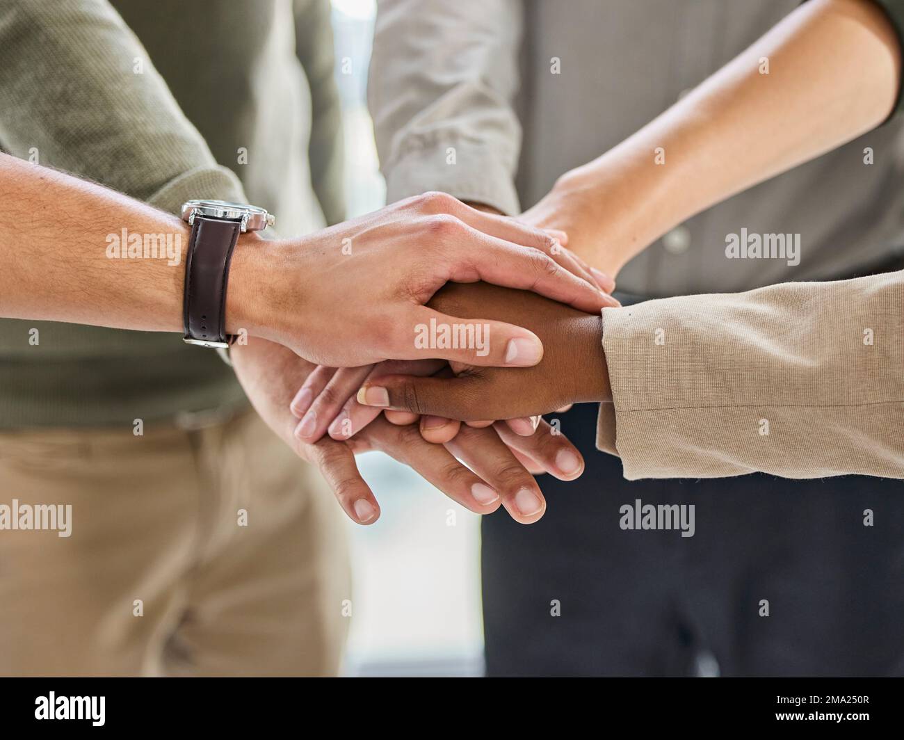 Stolz kommt vor dem Sturz. Eine Gruppe von unbekannten Geschäftsleuten, die ihre Hände in einem modernen Büro stapeln. Stockfoto