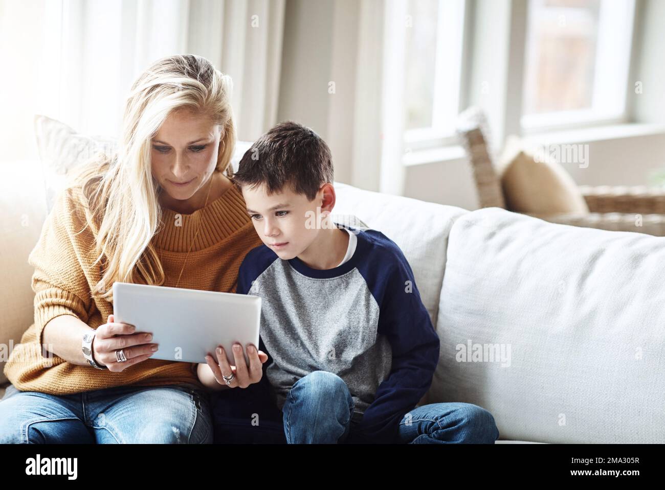 Tablet, Liebe und Mutter mit dem Jungen auf dem Sofa, schöne Zeit und Entspannung am gemeinsamen Wochenende. Familienheim, Lifestyle und mutter und Kind mit digitaler Technologie Stockfoto
