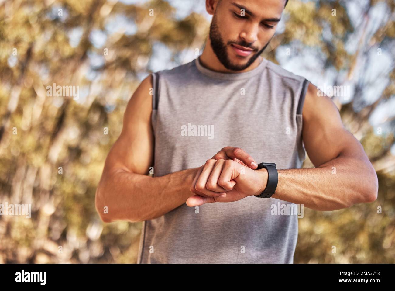 Ich möchte meine vorherige Zeit wirklich schlagen. Ein gutaussehender junger Mann, der allein steht und einen Timer auf seine Uhr stellt, bevor er rausläuft. Stockfoto