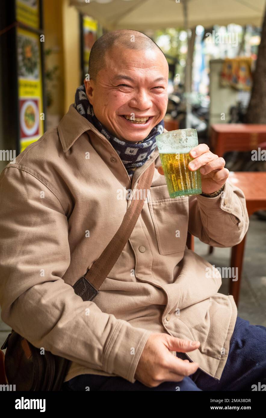 Ein vietnamesischer Mann trinkt ein Glas bia hoi oder frisches Bier auf