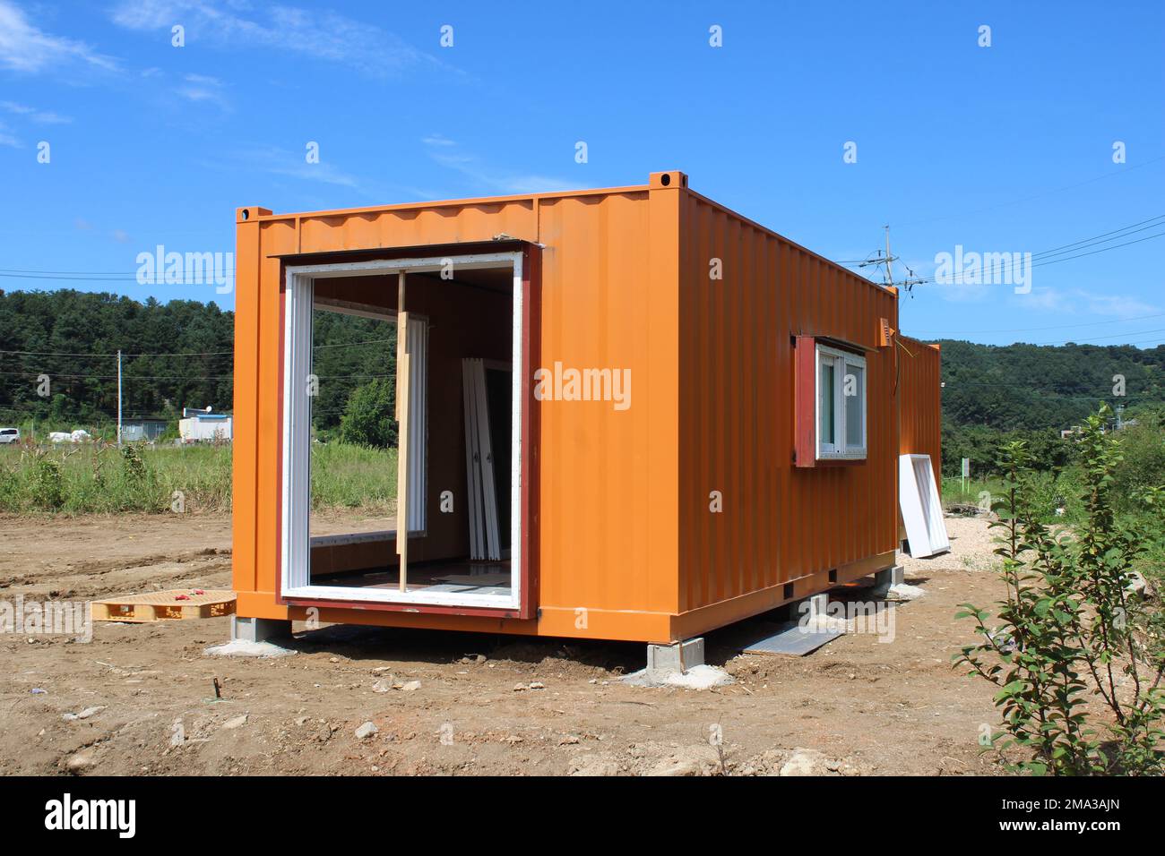 Orangefarbenes Versandcontainerbüro auf Baustelle auf dem Land Stockfoto