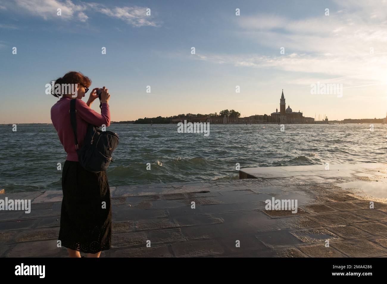 Eine Frau, die den Sonnenuntergang in Venedig fotografiert Stockfoto