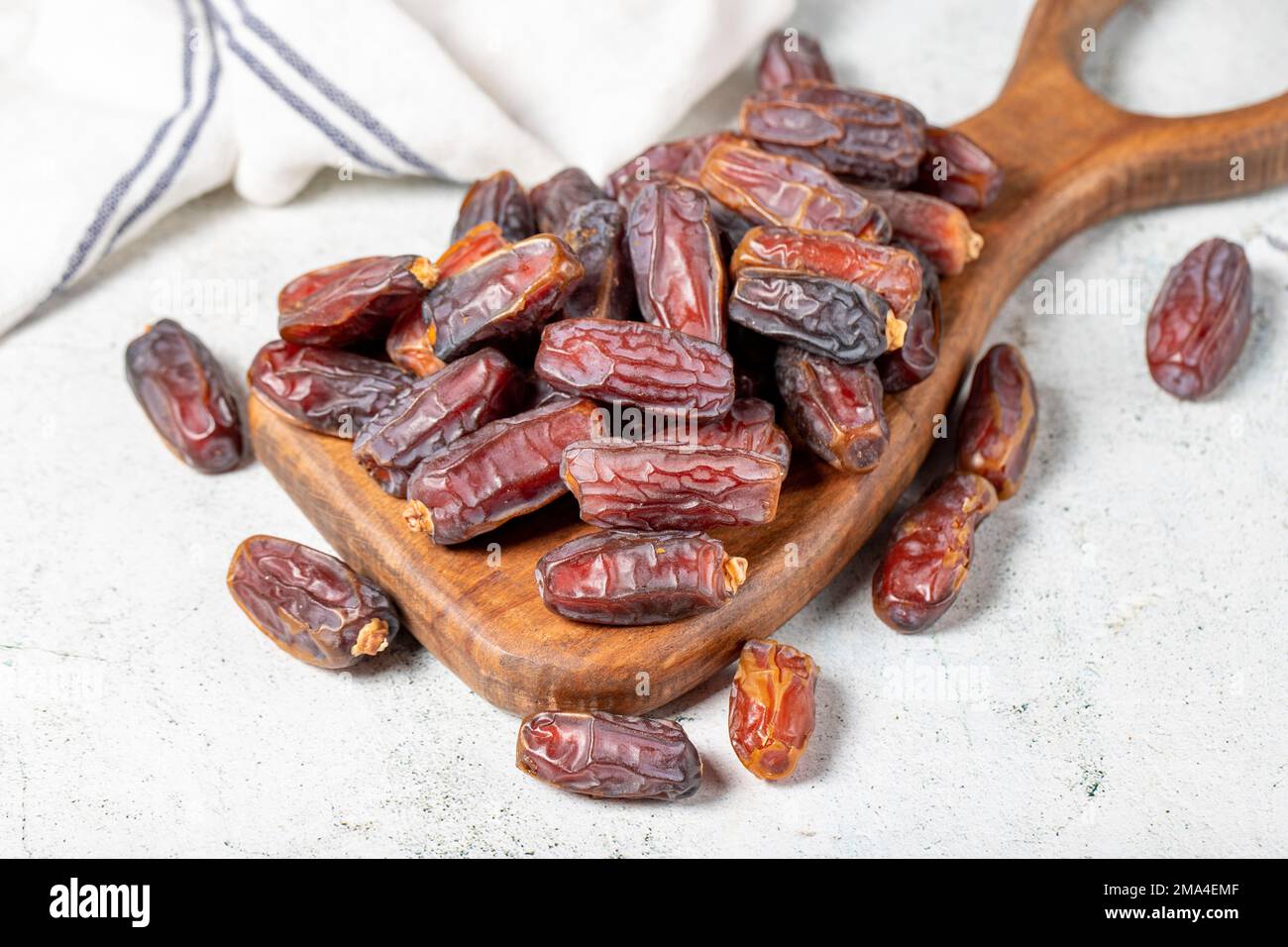 Dattelfrucht auf Steinhintergrund. Organischer Haufen Medjoul-Datteln auf einem Servierbrett aus Holz. Ramadan-Essen. Schließen Stockfoto