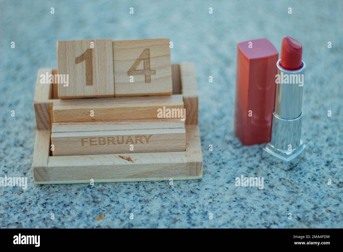 Holzkalender mit Valentinstag und Lippenstift für eine Frau, um sich auf ein Date mit ihrer Liebe vorzubereiten. Stockfoto