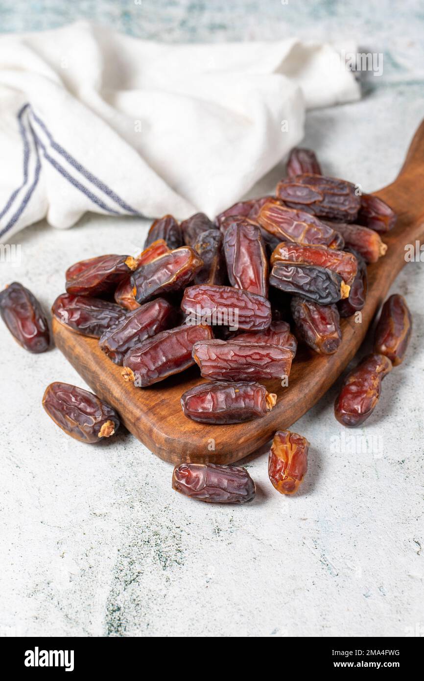 Dattelfrucht auf Steinhintergrund. Organischer Haufen Medjoul-Datteln auf einem Servierbrett aus Holz. Ramadan-Essen. Schließen Stockfoto