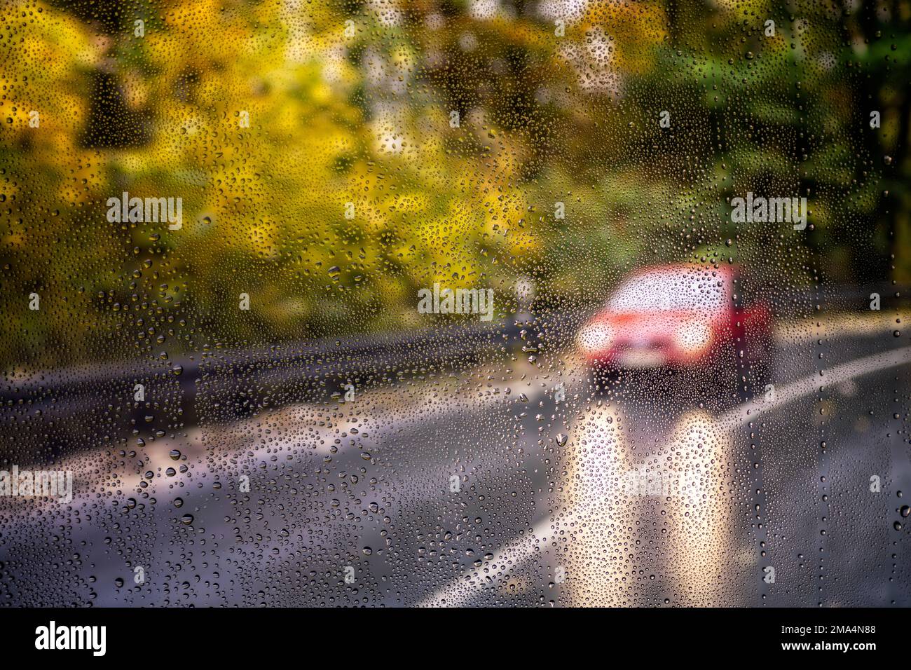 Blick durch eine regendurchflutete Windschutzscheibe eines entgegenkommenden Autos Stockfoto