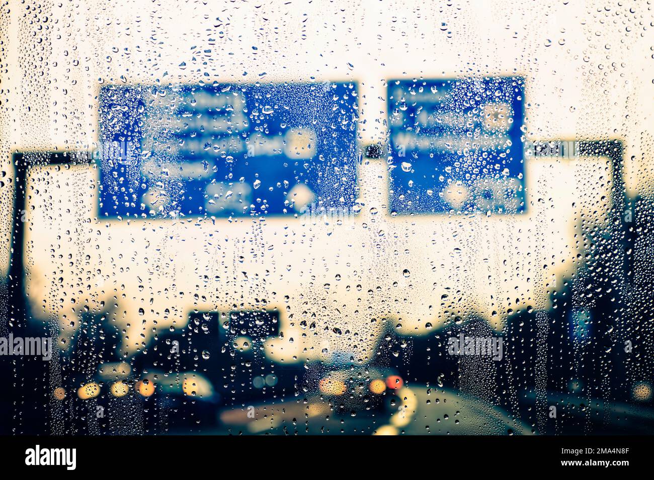 Fallenlassen auf einer regendurchfluteten Windschutzscheibe auf der Autobahn. Stockfoto