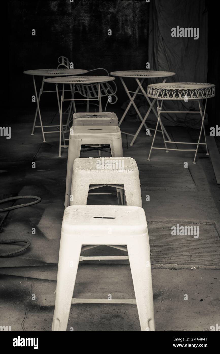 Eine Reihe von Plastikhockern und einige runde Tische im Hintergrund in einem Schuppen. Stockfoto