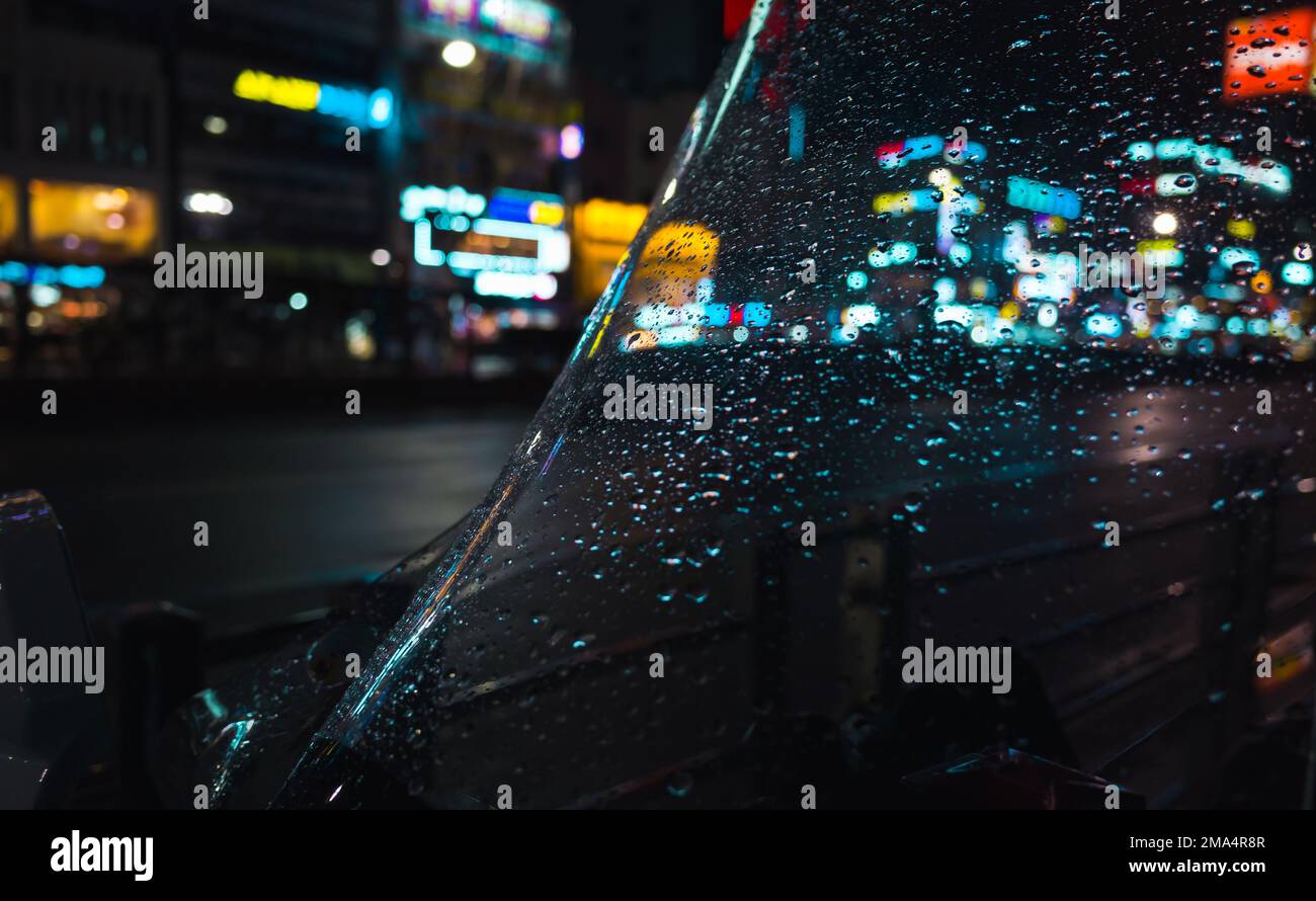 Abstraktes Hintergrundfoto der Stadt bei Nacht, verschwommene Straßenbeleuchtung und Regentropfen auf Glas Stockfoto