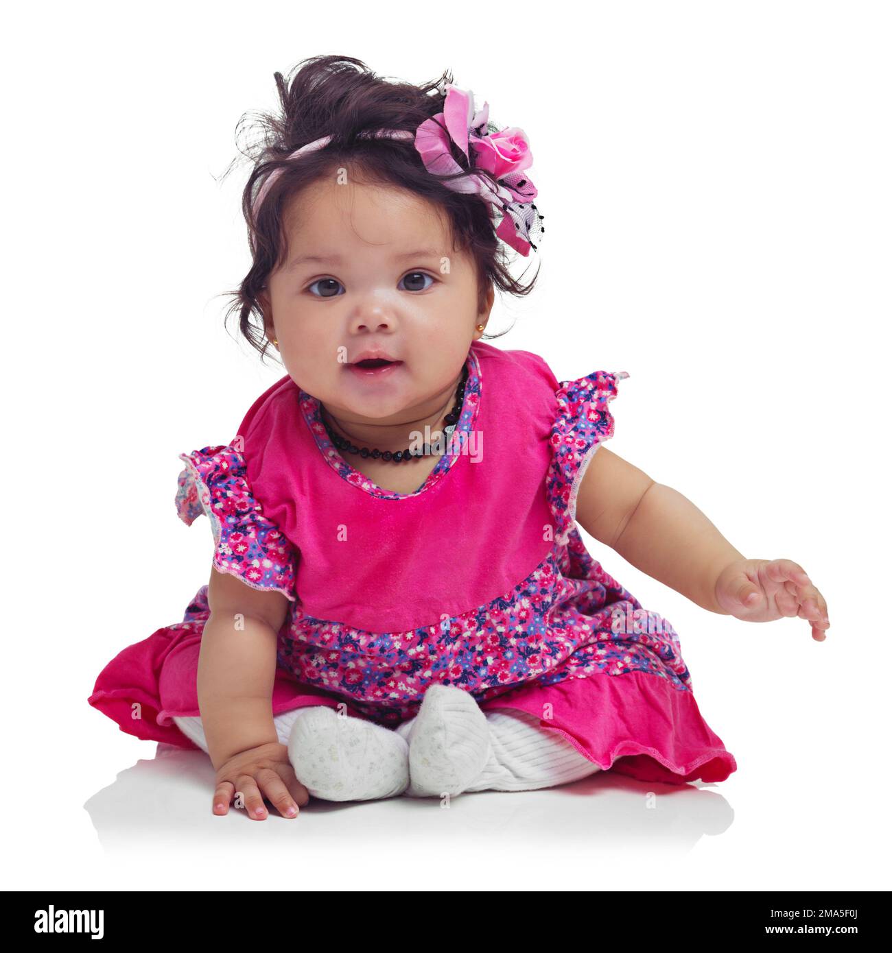 Süß, glücklich und Porträt eines kleinen Mädchens, das isoliert auf weißem Hintergrund in einem Studio sitzt. Mädchen, verspielt und unschuldig, liebenswert und kleines Kind Stockfoto