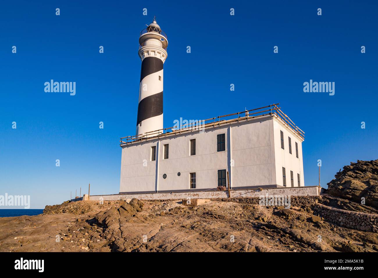 Blick auf die mondähnlichen Schieferfelsen und den Leuchtturm am idyllischen Cap de Favaritx, Menorca Island, Balearen, Spanien Stockfoto
