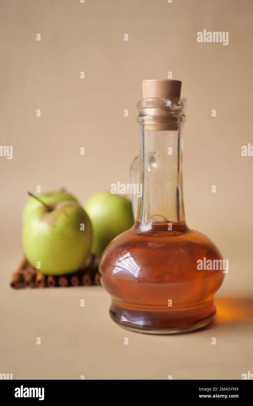 apfelessig in Glasflasche mit frischem grünen Apfel auf Tabelle Stockfoto