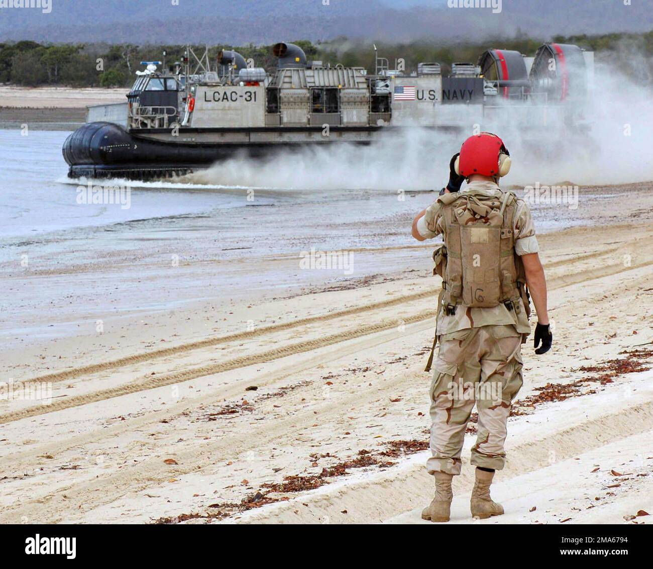 050619-N-3455P-002. [Complete] Szene Caption: Ein US Navy (USN) Beachmaster, Assault Craft Unit 5 (ACU-5), Marine Corps Base (MCB) Camp Pendleton, Kalifornien (CA), an Bord des USN Wasp Class Amphibious Assault Ship USS BOXERS (LHD 4), sieht ein USN Landing Craft, Air Cushion (LCAC) Fahrzeug fährt nach der Absetzung von Soldaten der australischen Armee am Sabina Point während der Übung TALISMAN Sabre 2005 ab. TALISMAN Sabre ist eine Übung, die gemeinsam vom US Pacific Command (USPACOM) und dem Joint Operations Command der Australian Defense Force gesponsert wird und zur Ausbildung des Personals des US-Befehlshabers der 7.-Flotte und dient Stockfoto