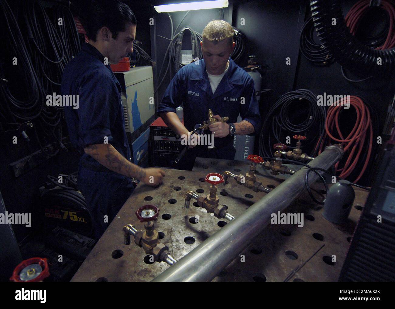 In der Maschinenwerkstatt gehen Sie an Bord der US Navy (USN) Nimitz Class, Aircraft Carrier, USS Harry S. Truman (CVN 75), Hull Mechanic Technician Fireman (HTFN) Steven Irwin (Vordergrund) und HTFN Chance Brooks und bereiten sich darauf vor, Stützen an einen Trinkwasserverteiler zu schweißen. Der Wasserverteiler wird zur Verteilung von Trinkwasser während der laufenden Hurrikanhilfsmaßnahmen entlang der Golfküstenregionen verwendet. Das USN unterstützt humanitäre Hilfsmaßnahmen unter der Leitung der Federal Emergency Management Agency (FEMA) in Zusammenarbeit mit dem Verteidigungsministerium (DOD). (Doppeltes Bild, siehe auch DNSD06007 Stockfoto