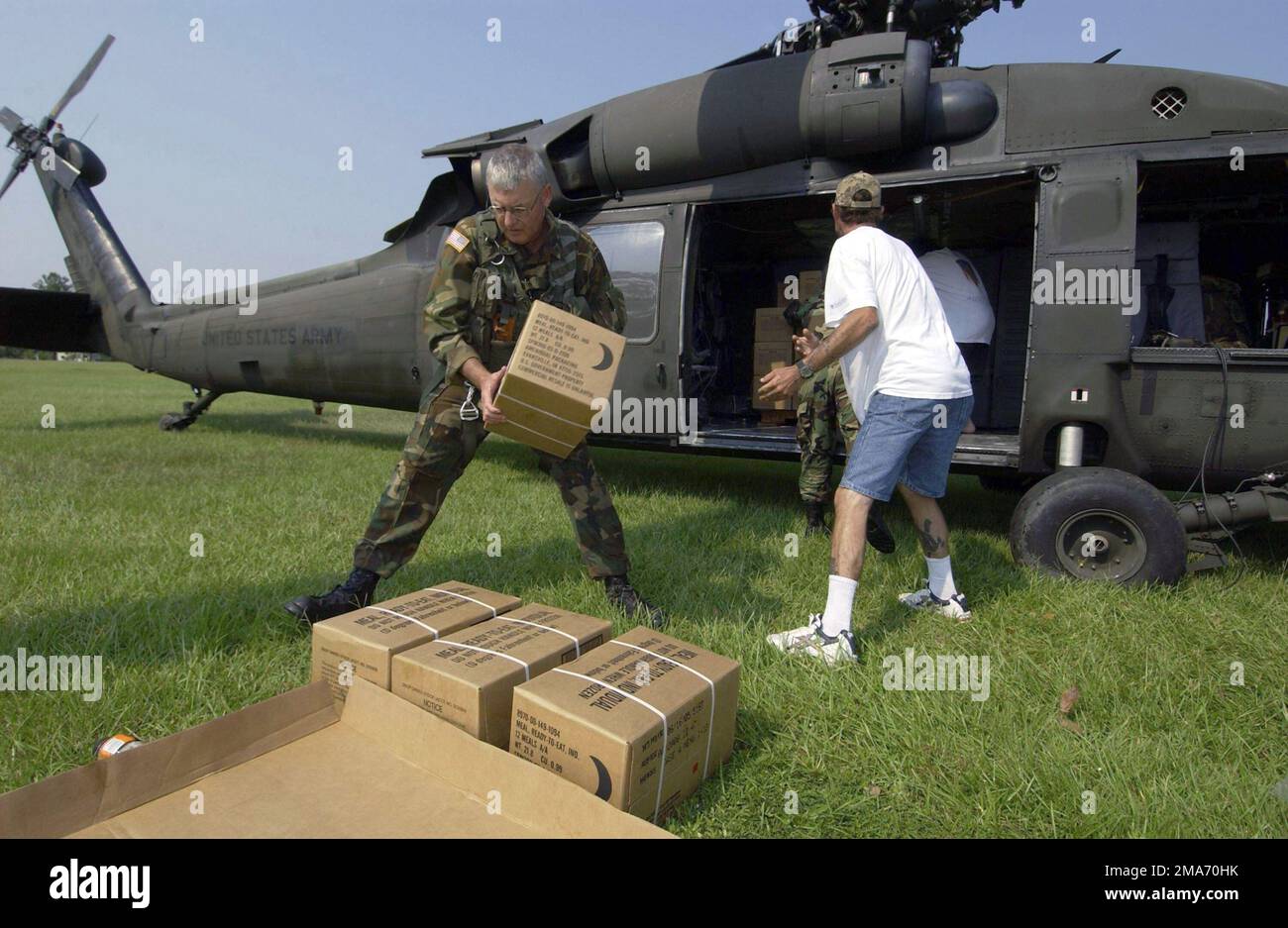 Mitarbeiter der US Army (USA) National Guard (ANG) aus Mobile, Alabama (AL), dem amerikanischen Roten Kreuz und Vertriebenen entladen Eisbeutel aus einem US UH-60 Black Hawk Helikopter zur Unterstützung des Hurrikan Katrina. Basis: Staat Vancleave: Mississippi (MS) Land: Szene der Vereinigten Staaten von Amerika (USA) Hauptkommando: NATIONALGARDE DER ARMEE Stockfoto