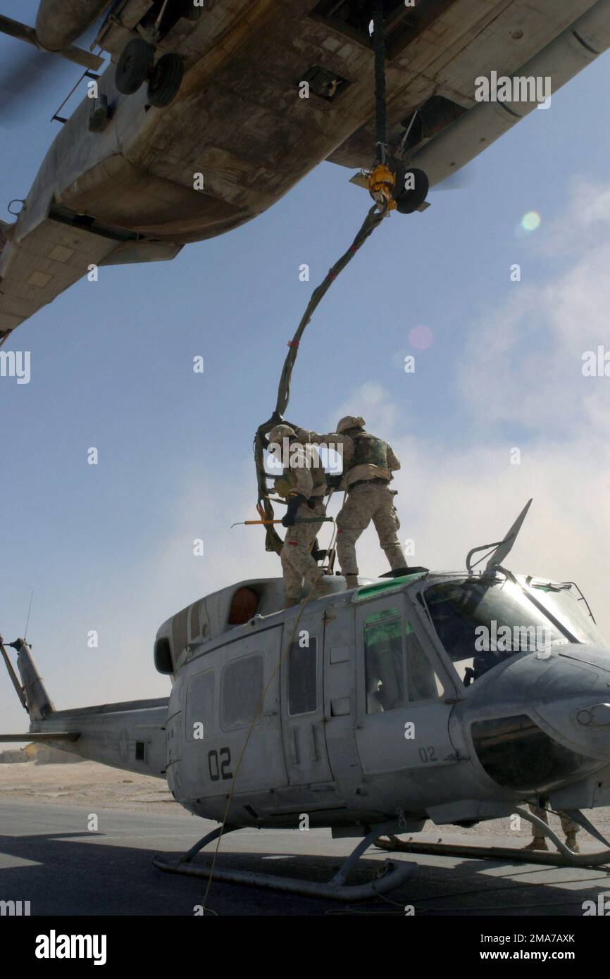 US Marine Corps (USMC) Marines vom Combat Logistics Battalion 2 (CLB-2) stehen auf einem USMC UH-1N Iroquois Huey, während sie es mit einem USMC CH-53 Super Hallion, Marine Heavy Helicopter Squadron 466 (HMH-466), Naval Air Station (NAS) Miramar, Kalifornien (CA) verbinden, für einen Aufzug aus dem Irak, Al Qaim Während der Operation IST die IRAKISCHE FREIHEIT. Basis: Al-Qaim-Staat: Al-Anbar-Land: Irak (IRQ) Stockfoto