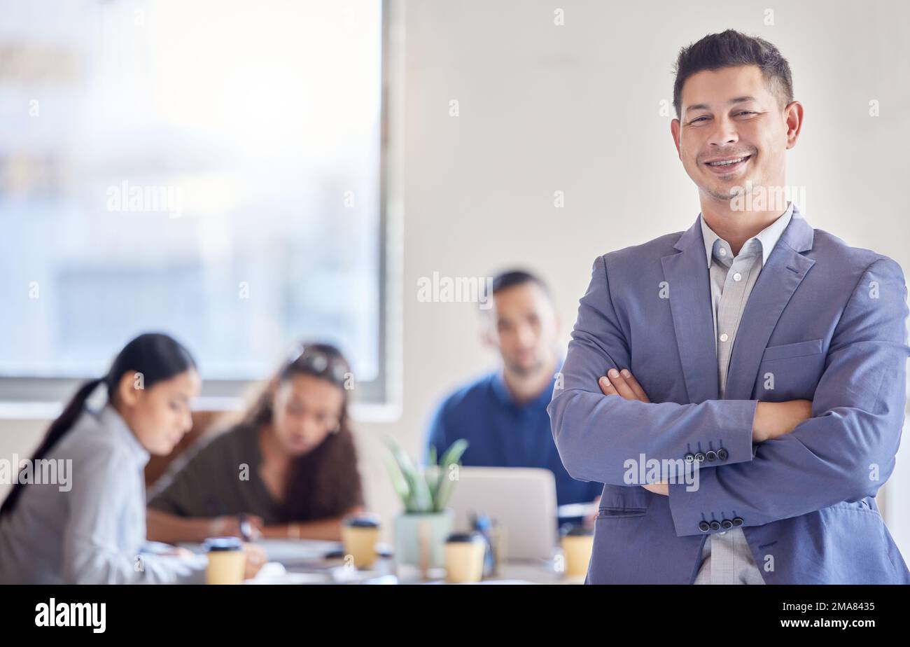 Dieses Geschäft ist meine Leidenschaft. Ein junger männlicher Geschäftsmann, der mit gekreuzten Armen in einem Büro auf der Arbeit steht. Stockfoto