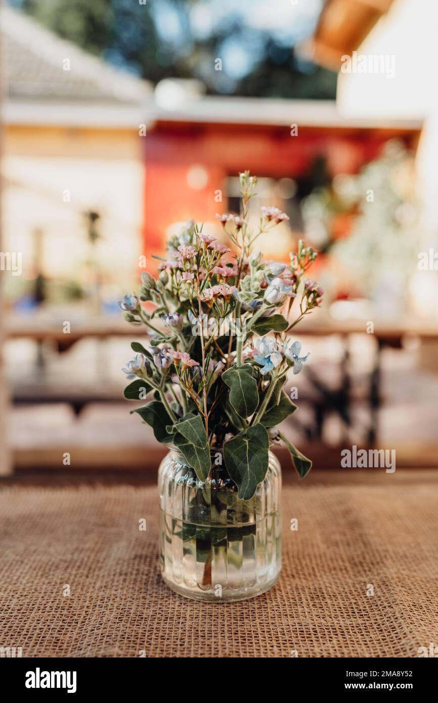 Schöne bunte Blumen in transparenter Vase aus Glas als Hochzeitsdekoration Stockfoto