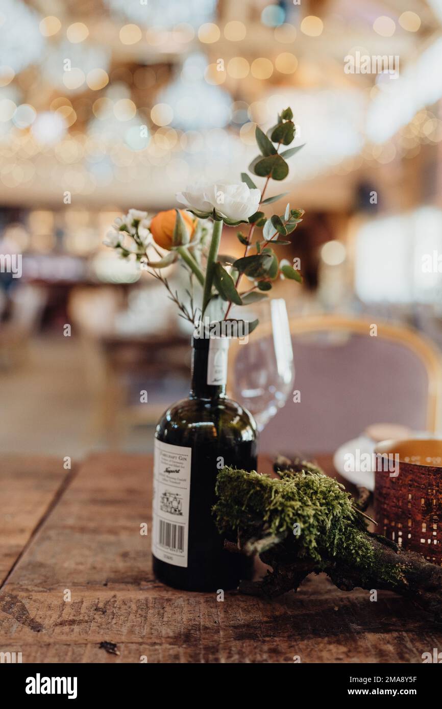 Schöne bunte Blumen in Ginflasche als Hochzeitsdekoration Stockfoto