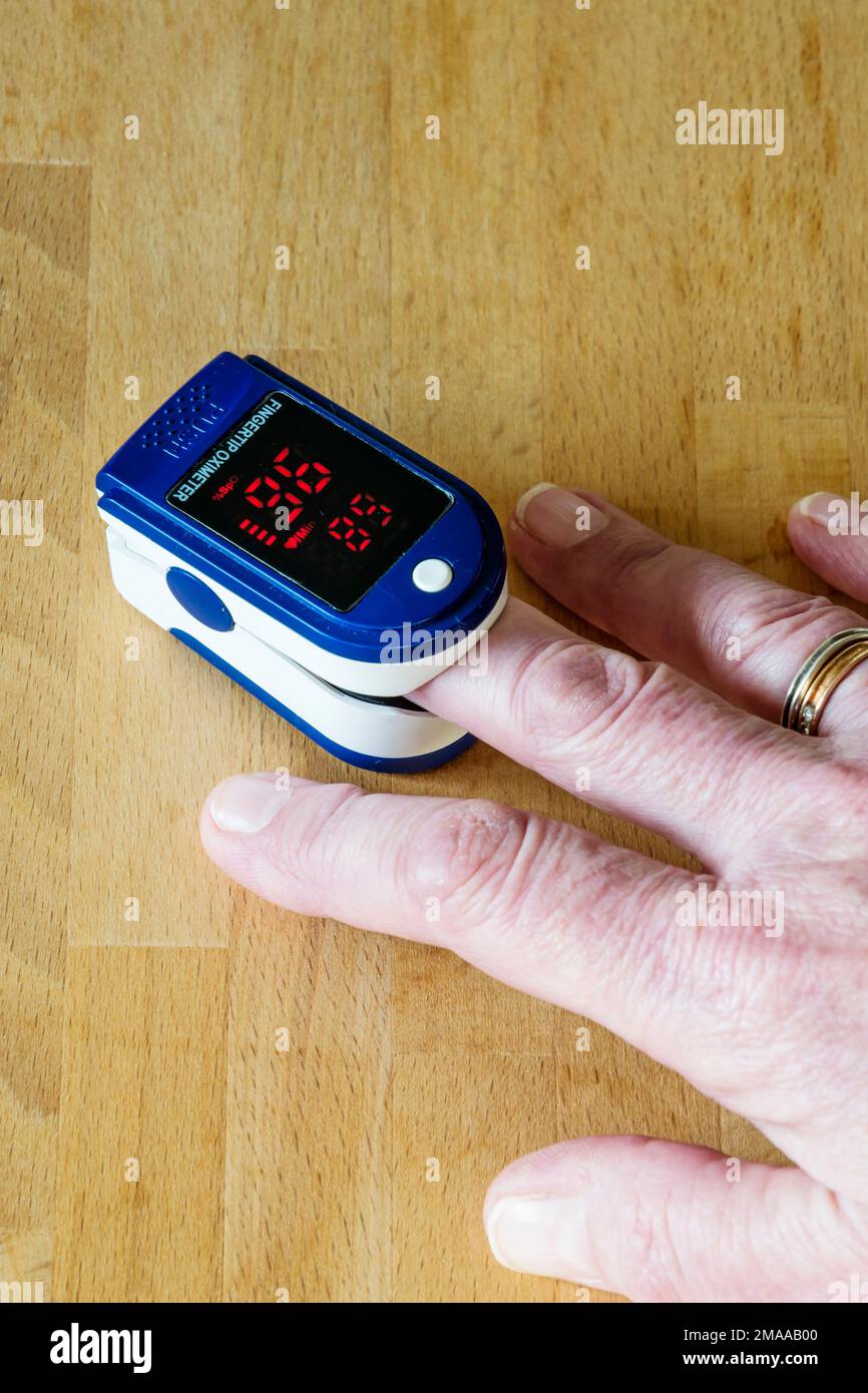 Eine Frau, die ein Pulsoxymeter benutzt, um die Sauerstoffmenge in ihrem Blut zu messen. Stockfoto