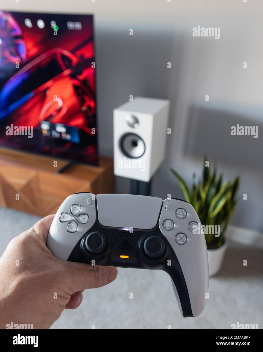 LONDON - 06. JANUAR 2023: Ein Mann, der im modernen Wohnzimmer mit PS5 PlayStation 5-Spielekonsolen-Controller spielt Stockfoto