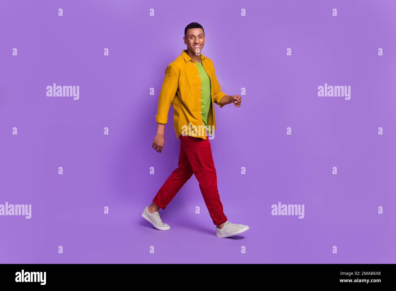 Das volle Profil Porträt eines zufriedenen, freundlichen jungen Mannes, der ein Lächeln strahlt und isoliert auf lila Hintergrund läuft Stockfoto